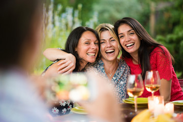 Fototapeta premium Three beautiful women posing for a photo around a terrace table