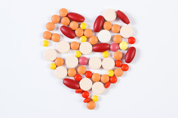 Heart shaped medical pills and capsules on white background, health care concept