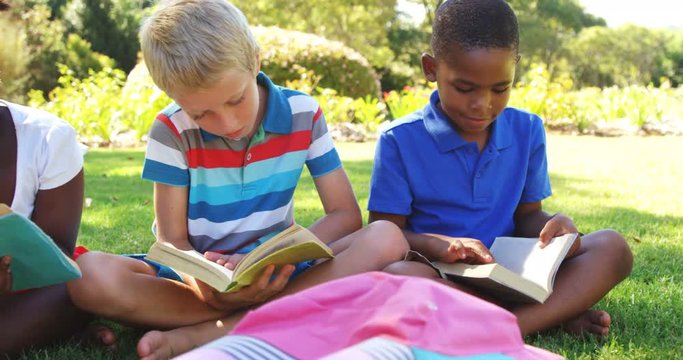 Group of smiling kids reading books in park on a sunny day 4k