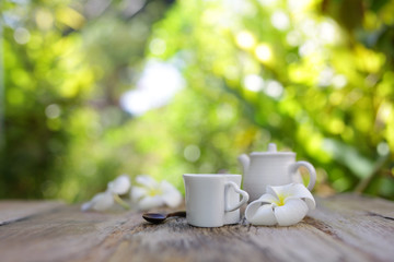 Flowers with heart shaped cup and tea pot on wooden table