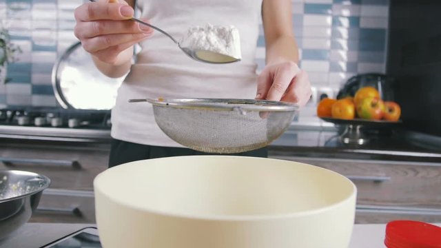 Young woman  sieve flour before kneading, slow motion, close up