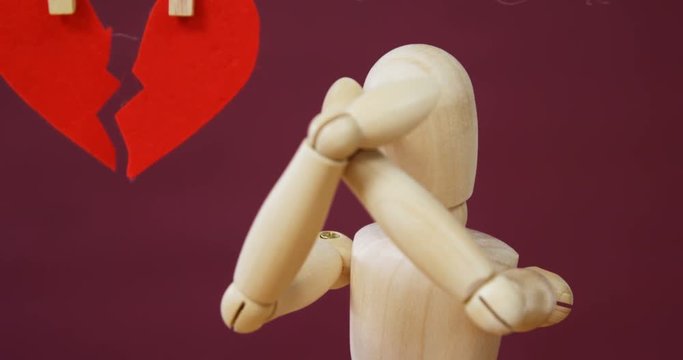 Conceptual image of figurine in front of broken heart 4k