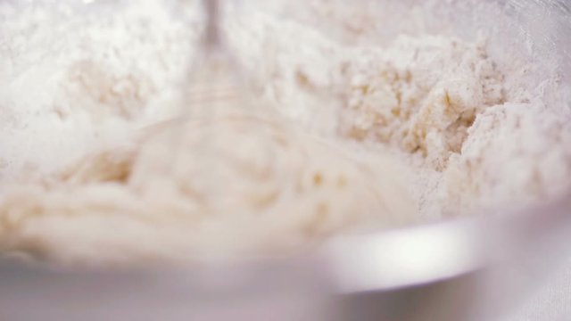 Young woman kneading dough with mixer, close up, slow motion