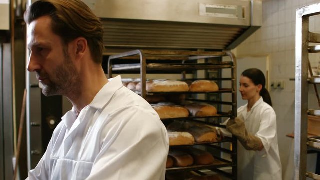 Bakers putting baked michetta in baking trolley at bakery kitchen 4k