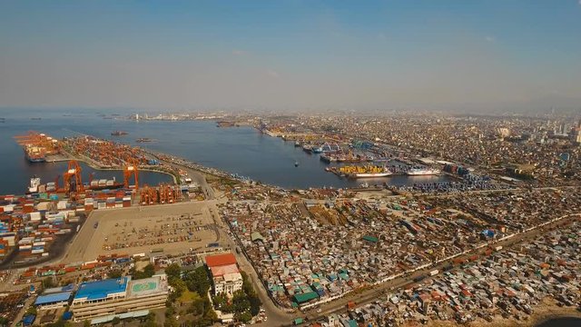 Aerial view industrial cargo port with ships and cranes. View of the cargo port and container terminal. Aerial footage container cranes in Manila Bay. Cargo ship in industrial port. Manila