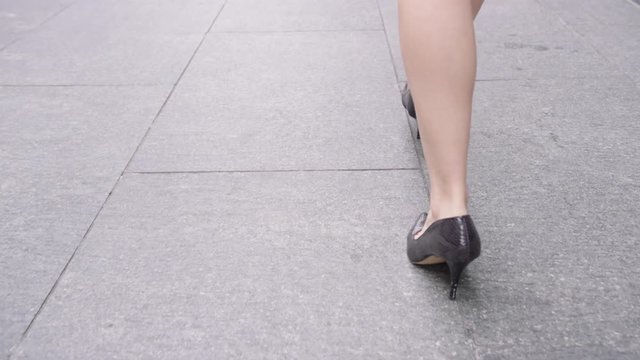 Close-up businesswomanâ€™s feet in heels walking down pavement in city to work