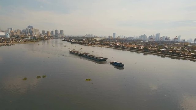 Aerial view tugboat pushes barge in the Bay of Manila.Aerial footage Tugboat and ship inside the harbor. Barge loaded with floats in the sea. 4K video. Philippines, Manila.