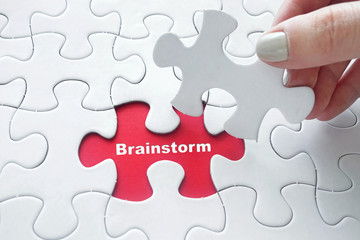 Fototapeta premium Close up of girl's hand placing the last jigsaw puzzle piece wit
