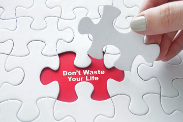 Fototapeta premium Close up of girl's hand placing the last jigsaw puzzle piece wit
