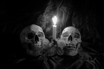 Skull with Bunch of flowers and candle light on wooden table with black background in night time in...
