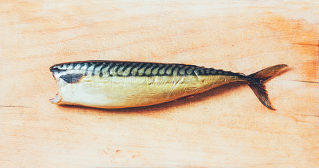 Smoked mackerel without a head on a wooden cutting board, top view close-up