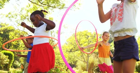 Group of kids twirling hula hoop in park on a sunny day 4k - Powered by Adobe