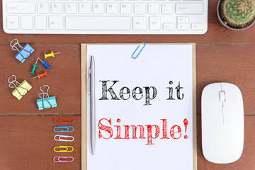 Text Keep it simple on white paper which has keyboard mouse pen and office equipment on wood background / business concept.