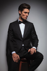 side view of an elegant  man wearing tuxedo sitting