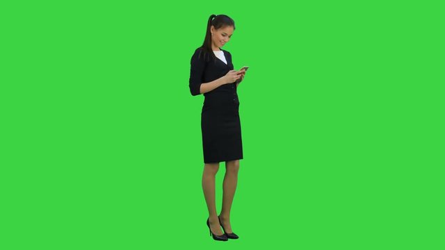 Happy young woman flattered by compliments sent to her mobile phone on a Green Screen, Chroma Key