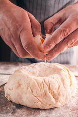 Cracking egg and adding it in dough close-up. Cooking process of preparing tasty pastry, baker mixing ingredients by recipe. Homemade bakery, kitchen, culinary concept