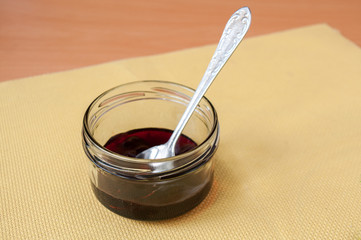 Spoon in a jar of cherry jam on the table