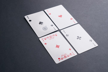 High Angle View of Four Playing Cards Spread Out on Dark Background Showing Aces from Each Suit - Hearts, Clubs, Spades and Diamonds