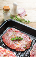 Raw fresh meat steak with rosemary leaves and salt on wood