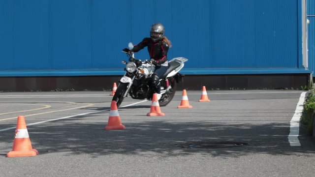 Motorcyclist does exercise with cones on the motorbike on the skill training asphalt motordrome. Russian driver school
