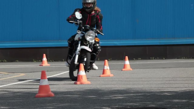 Motorcyclist makes wave-driving exercise with cones on the motorbike on the skill training asphalt motordrome. Russian driver school
