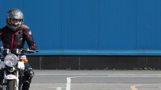 Young woman motorcyclist does exercise on the motorbike on the skill training motordrome. Russian driver school

