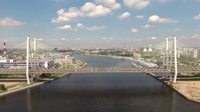 Side aerial view of cable stayed Bolshoy Obukhovsky bridge across Neva river. Clip with timelapse part. Flying to highway. St. Petersburg, Russia
