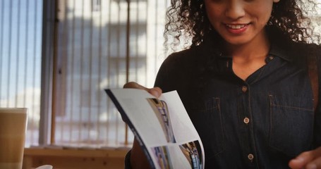 Smiling woman reading magazine while having coffee in cafÃ© 4k - Powered by Adobe
