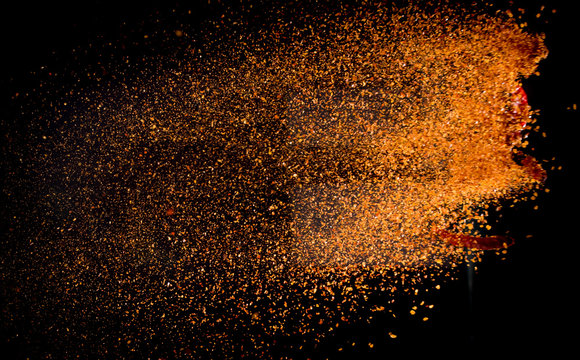Cayenne pepper powder explosion isolated on black background
