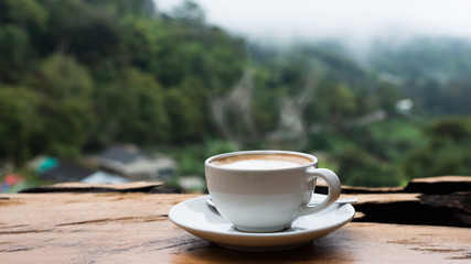 Hot coffee cappuccino cup with milk foam on wood table.