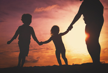 silhouette of family with kids play at sunset beach