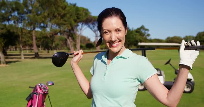 Happy golfer carrying golf club on shoulder while standing on the golf course