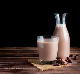 Glass of chocolate milk on wood table,dark background