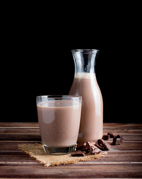 Glass of chocolate milk on wood table,dark background
