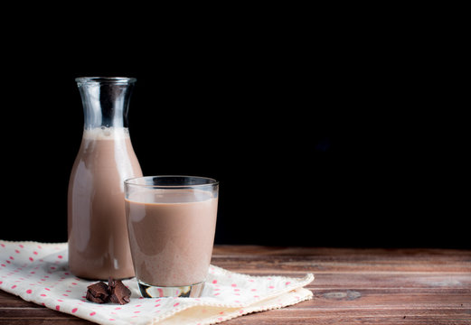 Glass of chocolate milk on wood table,dark background