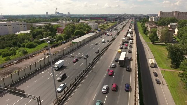 Vehicles drive at teh lanes of city highway, aerial view. Orbital freeway encircling city is in Rybatskoye municipality, Nevsky district