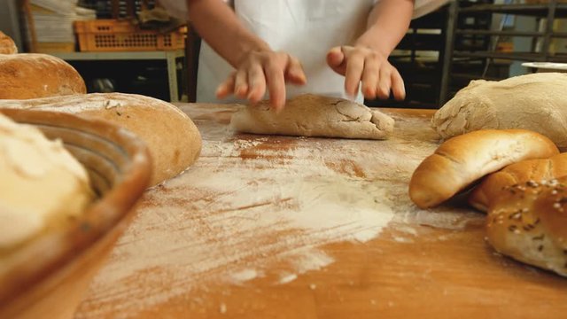 Mid section of female baker kneading a dough in bakery shop 4k