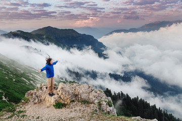 young happy woman enjoying view of a great foggy landscape on mountain peak
