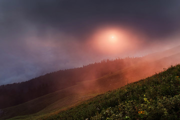 Fototapeta premium beautiful sunset in the mountains with fog and clouds and small houses shepherds