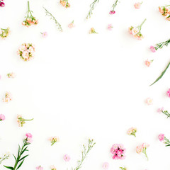 Fototapeta premium Frame with pink and beige wildflowers, green leaves, branches on white background. Flat lay, top view. Valentine's background