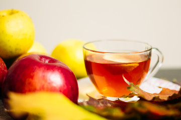 Cup of tea with lemon next to ripe apples