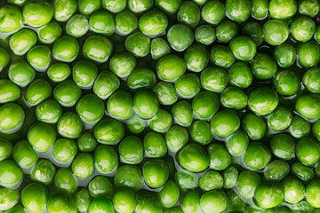 Wet fresh green peas in water closeup as background. Healthy vitamin food.
