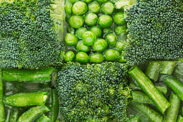 Fresh frozen green peas, french bean, broccoli with hoarfrost closeup as decorative chess background. Healthy vitamin food.
