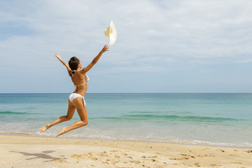 Woman on the beach is throwing her hat
