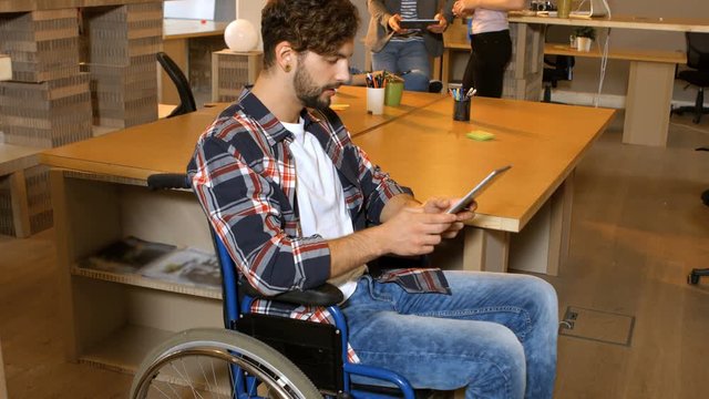 Male business executive sitting on wheelchair and using digital tablet in office 4k