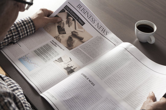 Senior man reading newspaper on table