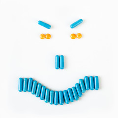 Angry smile made from many pills and capsules. wellness concept