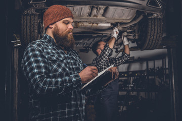 Bearded mechanics male inspecting car.