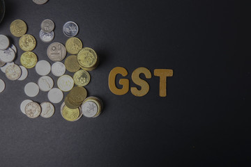 Coins on blackboard  with word GST (government service tax). Business concept