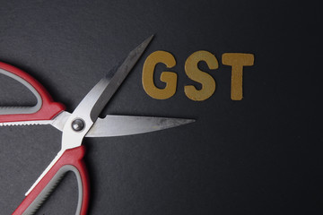 Scissors and word of GST on black background